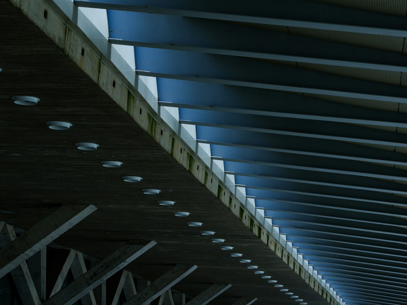 The geometric underside of a concrete bridge against a blue sky